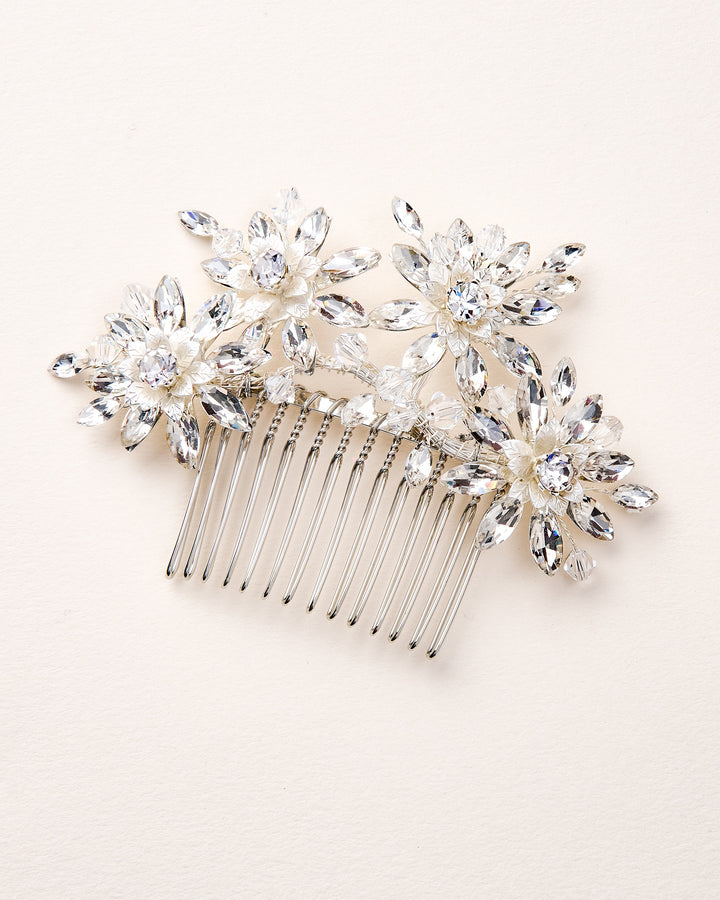 Silver hair comb with crystal flower decorations on a light pink background