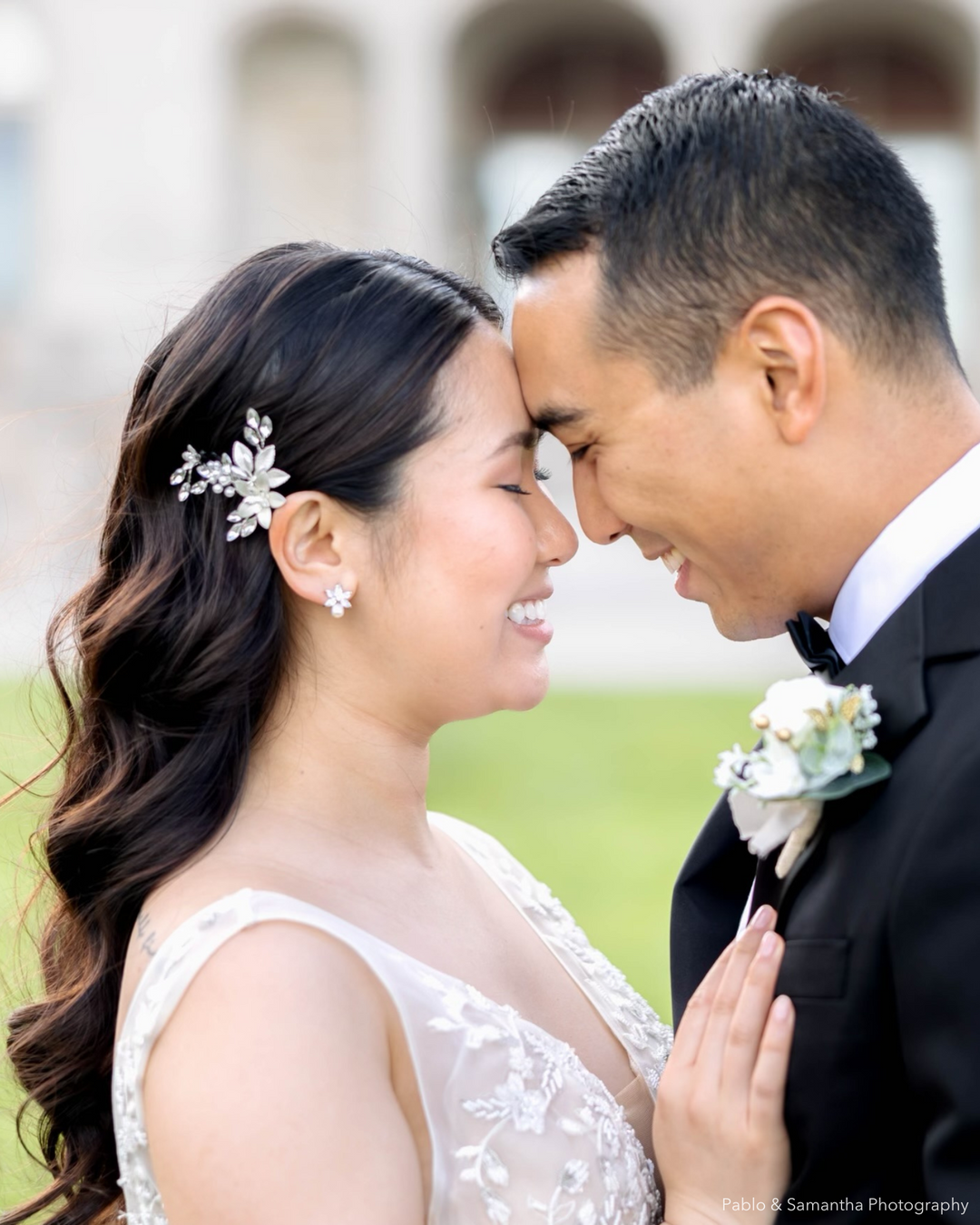 Bride wearing earrings and floral hair pin on her wedding day with groom