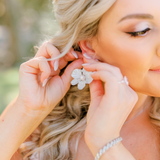 Bridal earrings shaped like flowers on a bride