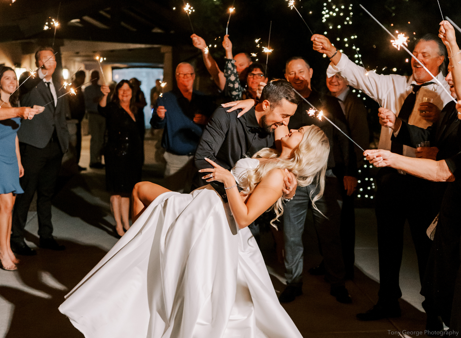 Bride and groom kissing under sparklers on wedding day with bride wearing Dareth Colburn wedding accessories