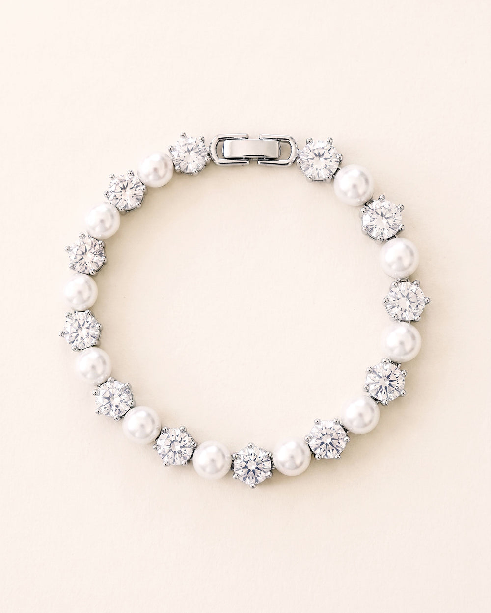 Close-up of prong-set cubic zirconia and ivory pearls on a quarter-inch wide silver bracelet