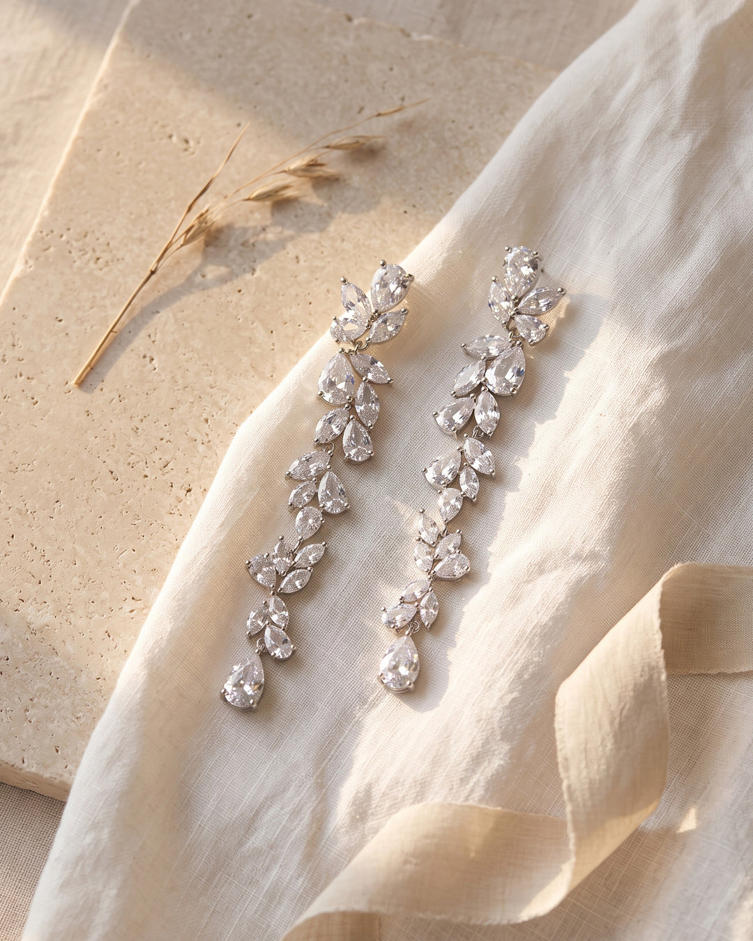 Anastasia earrings laid on linen and stone showing marquise and pear cubic zirconia up close