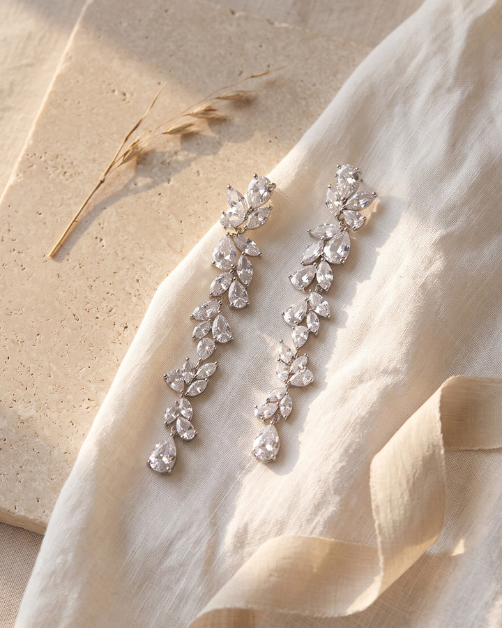 Anastasia earrings laid on linen and stone showing marquise and pear cubic zirconia up close