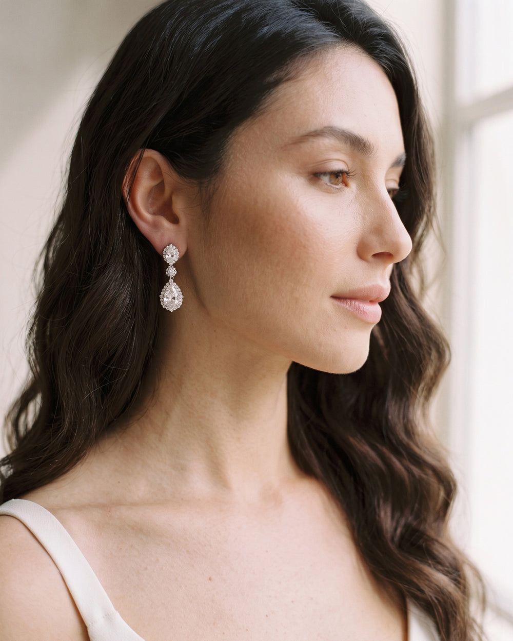 Close profile of a bride with dark waves wearing the Emerson halo teardrop earrings