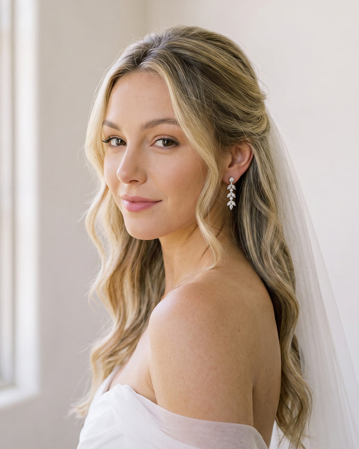 Bride in a wedding gown and veil wearing the silver Sydney CZ drop earrings with soft waves