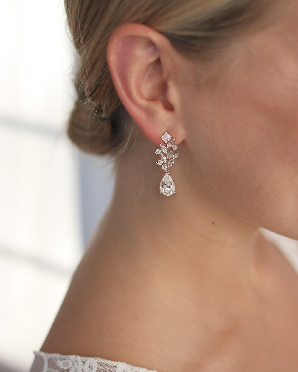 Close-up of an Anna CZ earring on the ear, marquise vine leading to a pear-shaped drop, worn with a low bun