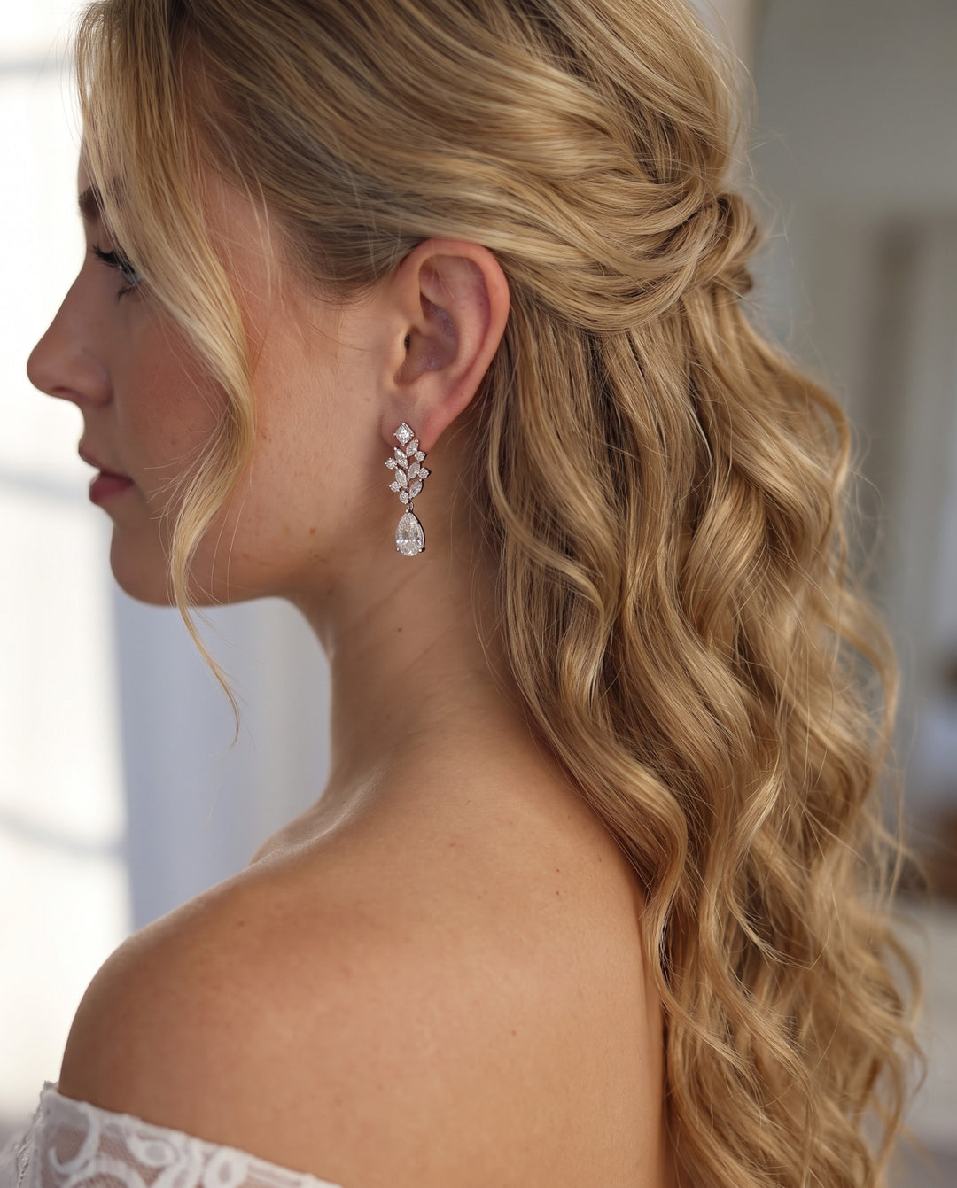 Bride in an off-the-shoulder lace gown wearing Anna cubic zirconia wedding earrings with long half-up waves