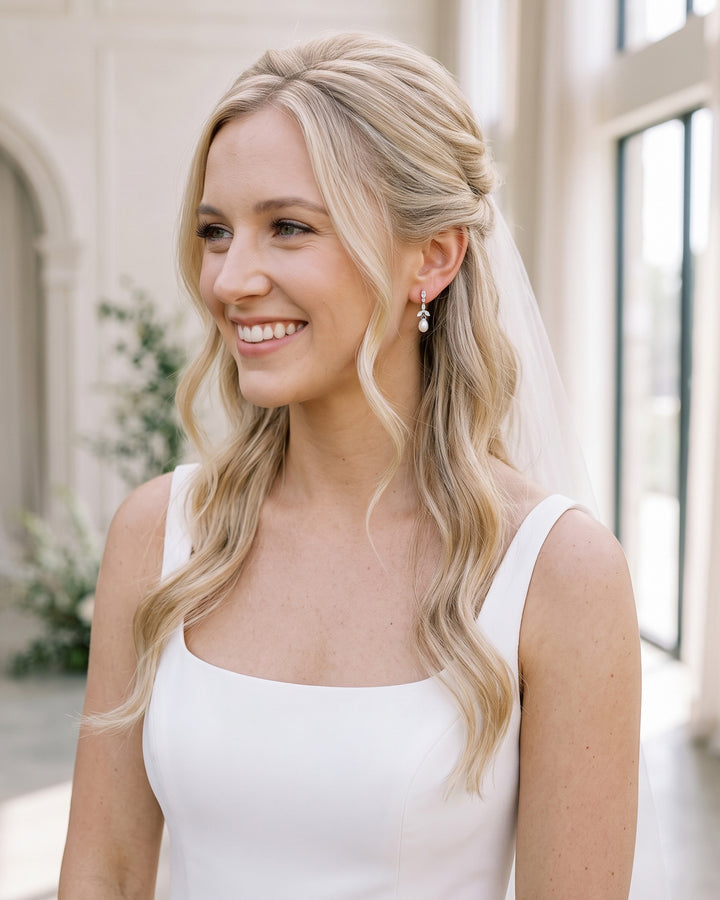 Smiling bride with half-up waves and a veil wearing the Olivia pearl wedding earrings