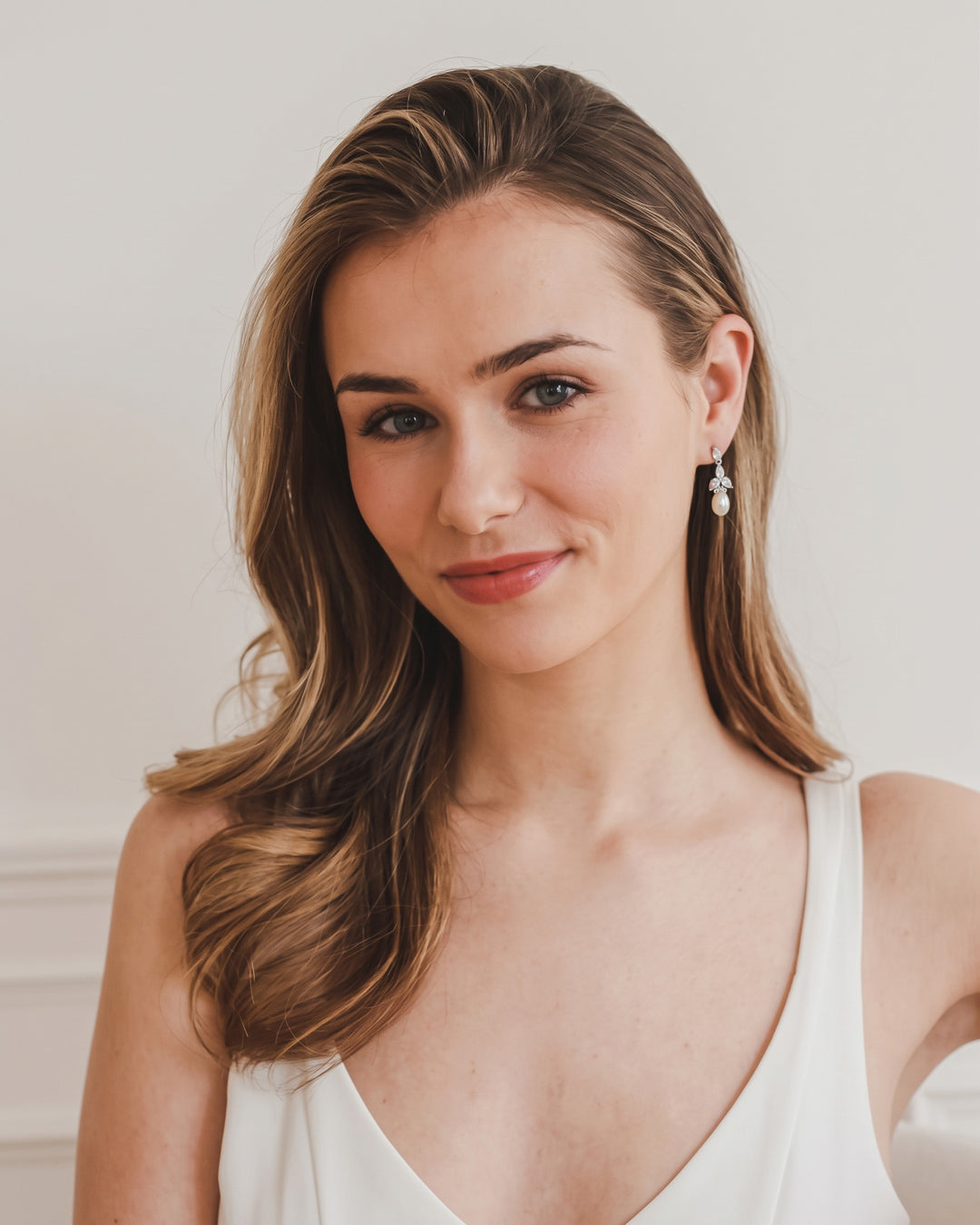 Model with long side-swept hair wearing the silver Olivia pearl drop earrings