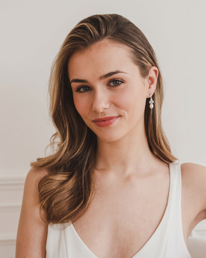 Model with long side-swept hair wearing the silver Olivia pearl drop earrings