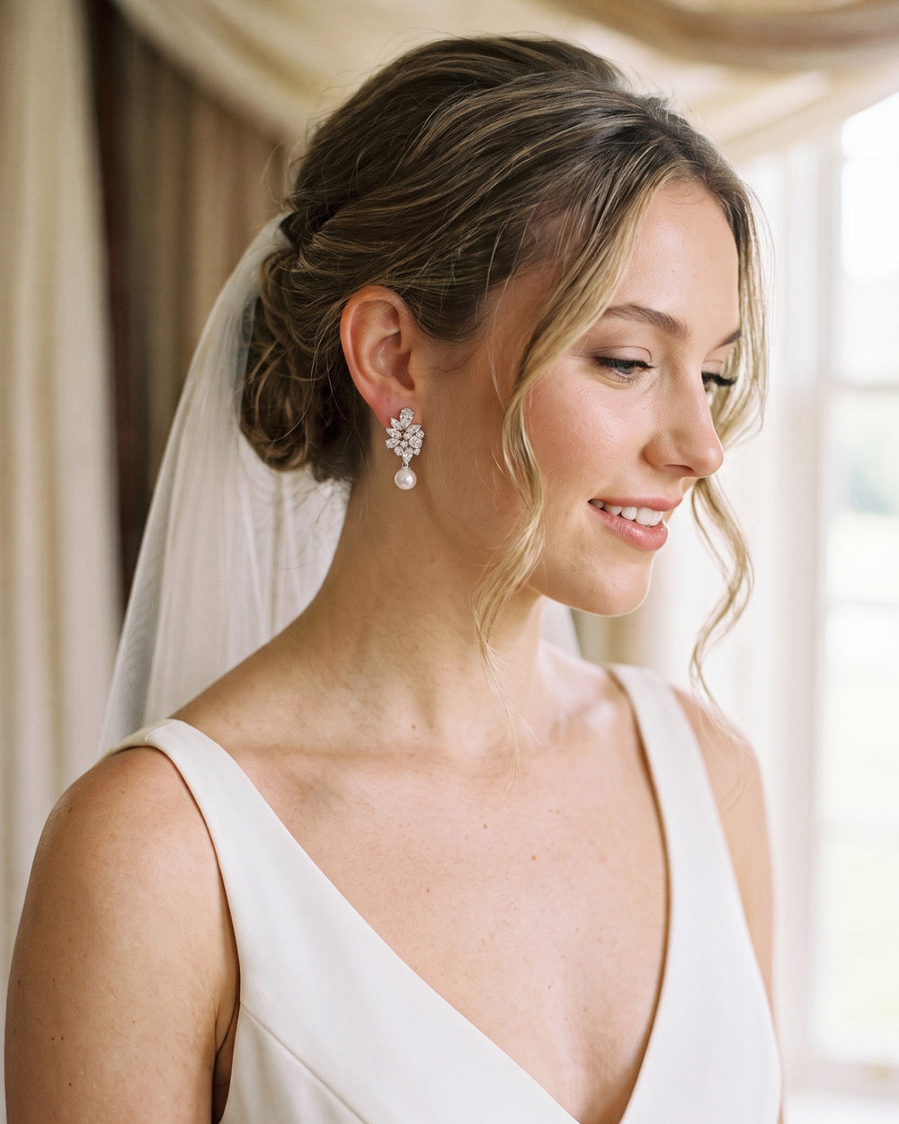 Bride in a veil and V-neck gown wearing the Serenity CZ and pearl wedding earrings