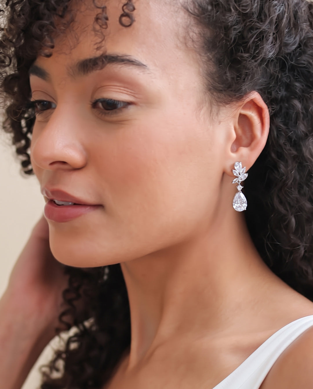 Bride with natural curls wearing the Madison pear drop earrings, shown close in profile