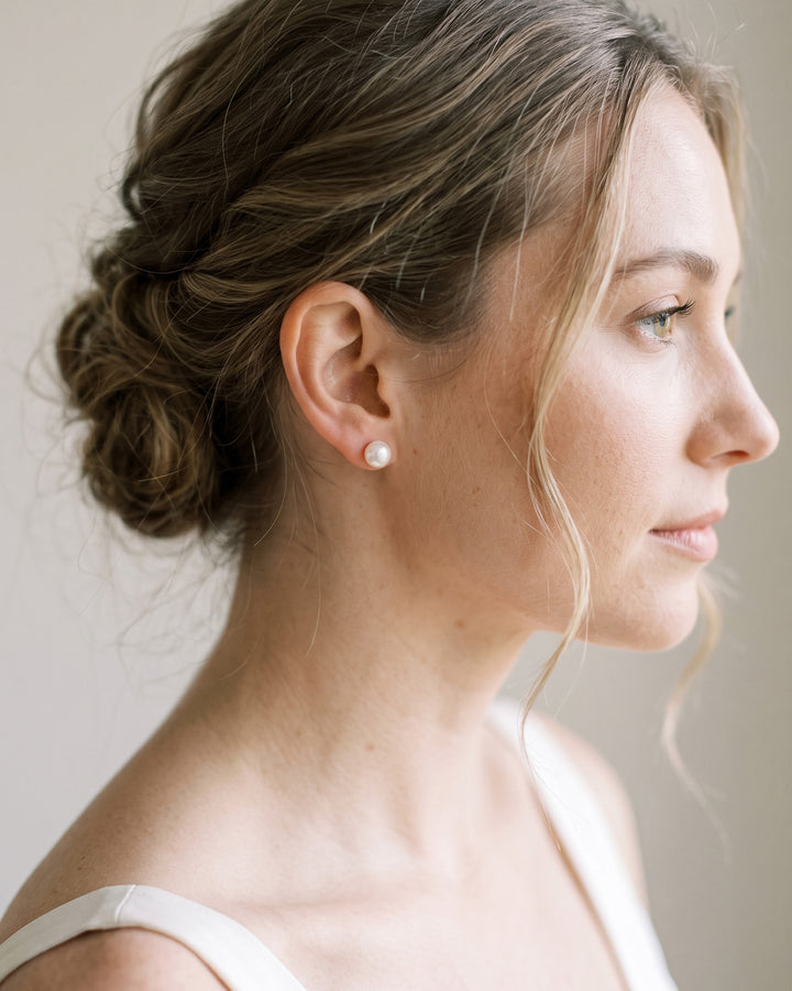 Bride in profile with a low updo wearing classic pearl stud earrings