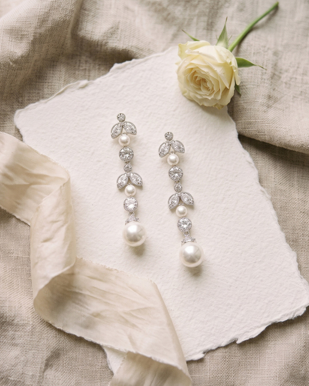 Sabrina pearl drop earrings on handmade paper with ivory ribbon and a white rose