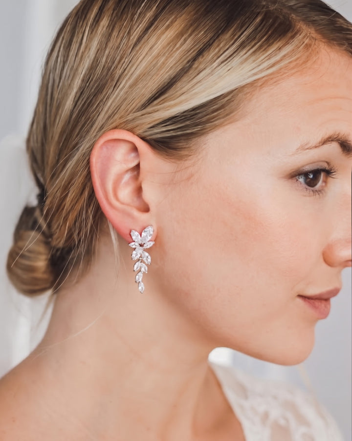 Profile of a bride with a low bun wearing the Nicole cascading CZ wedding earrings in silver