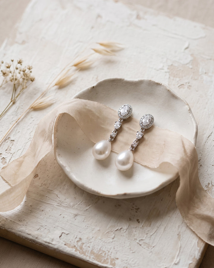 Adele pearl drop earrings on a ceramic dish with silk ribbon and dried flowers