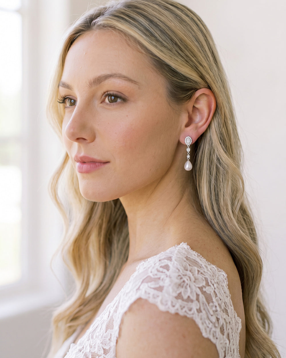 Blonde bride with long waves in a lace gown wearing Adele pearl and CZ drop earrings