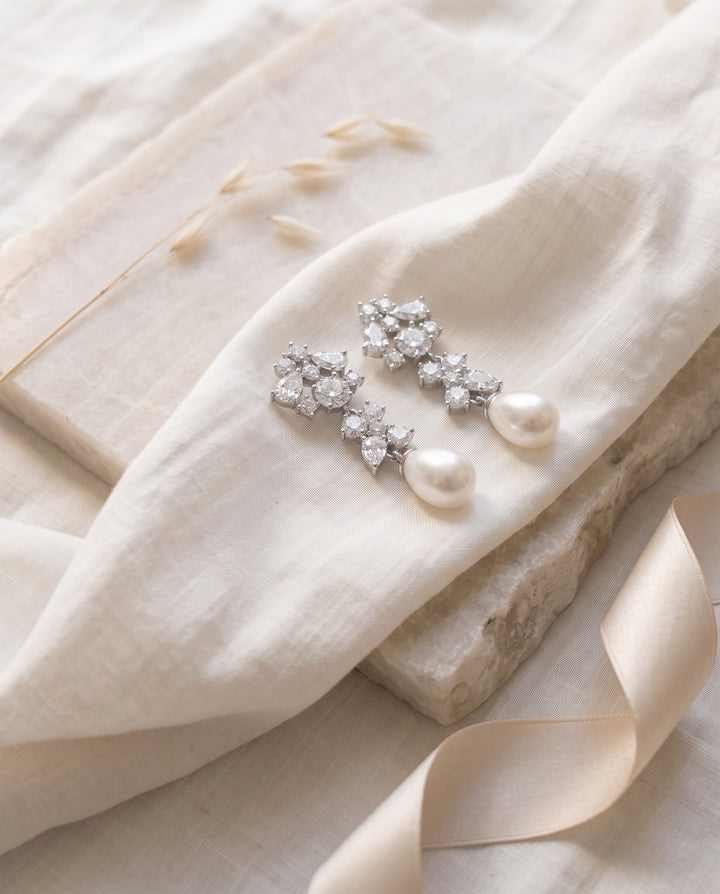 Silvia earrings on linen and stone showing the pearl drops and marquise CZ up close