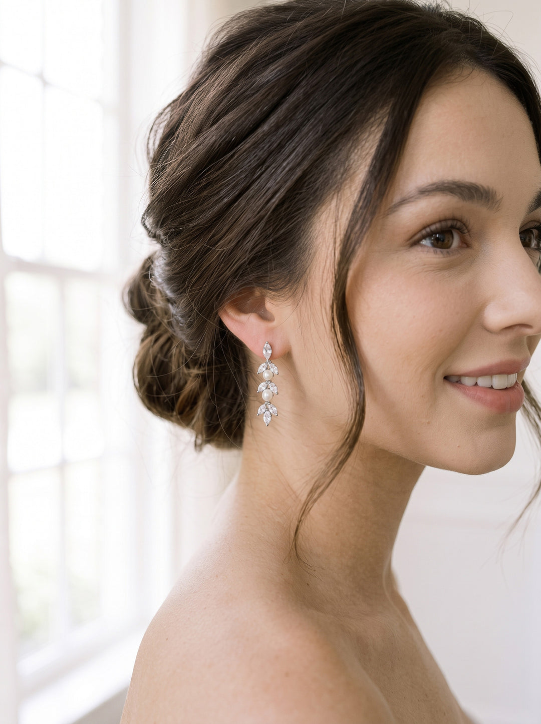 Close-up of the Sydney Pearl CZ drop earring with a brunette bride's soft low updo