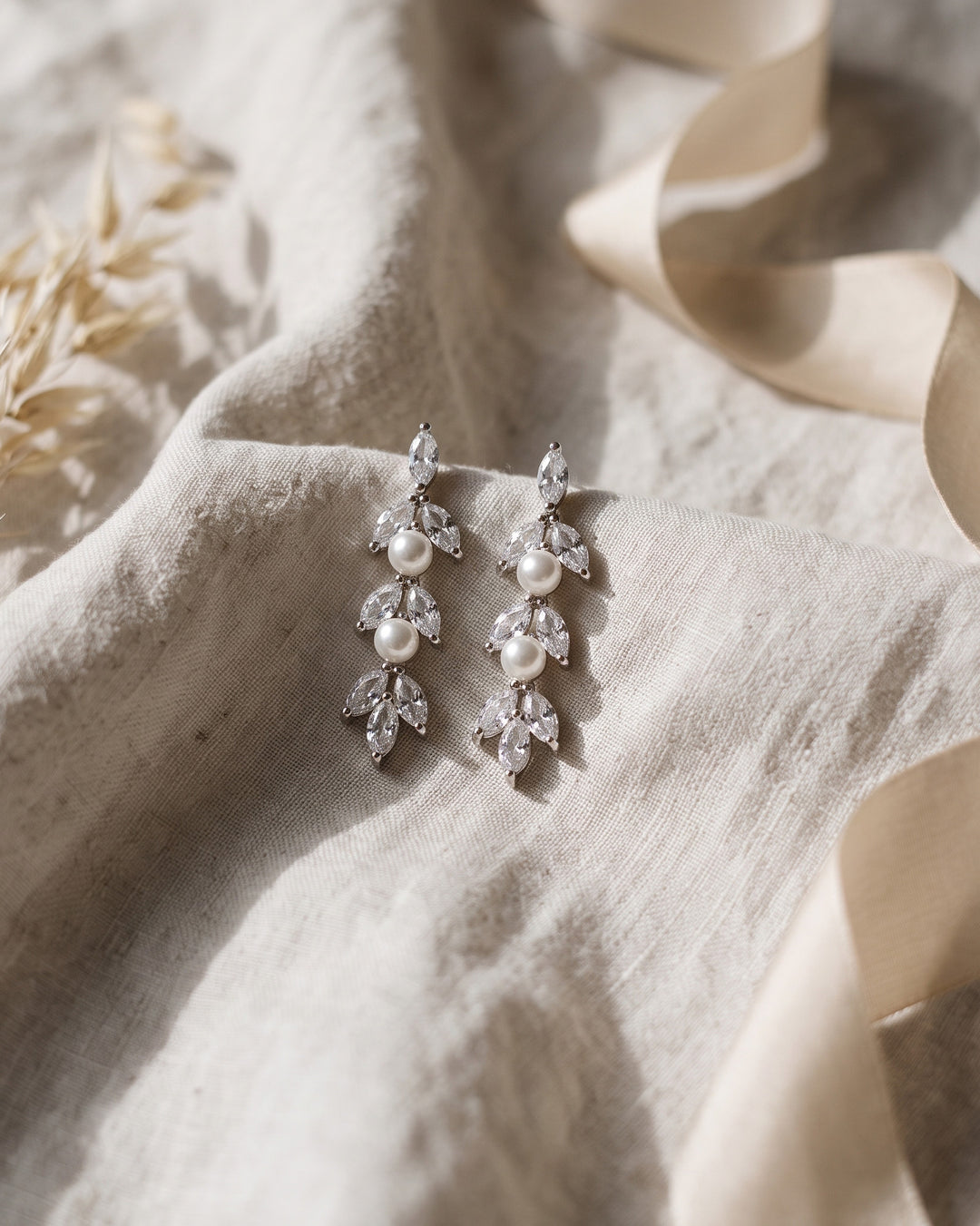 Silver Sydney Pearl earrings on soft linen, showing pearls set between marquise CZ leaves