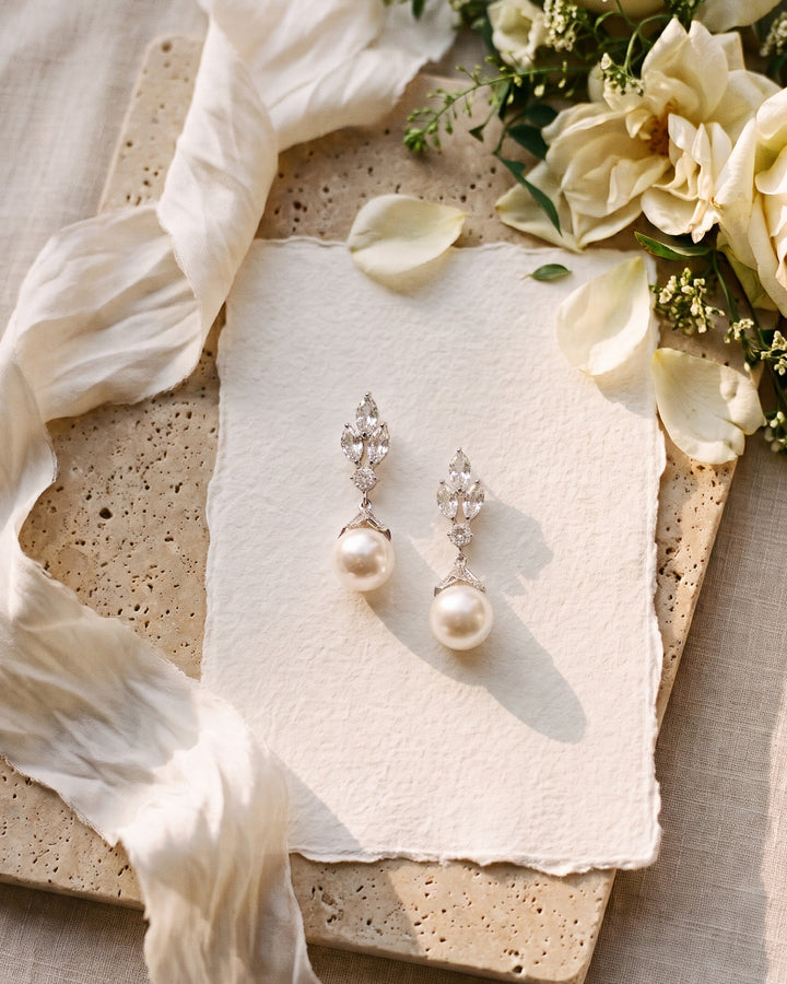 Bethany wedding earrings on deckle paper beside cream roses and a silk ribbon