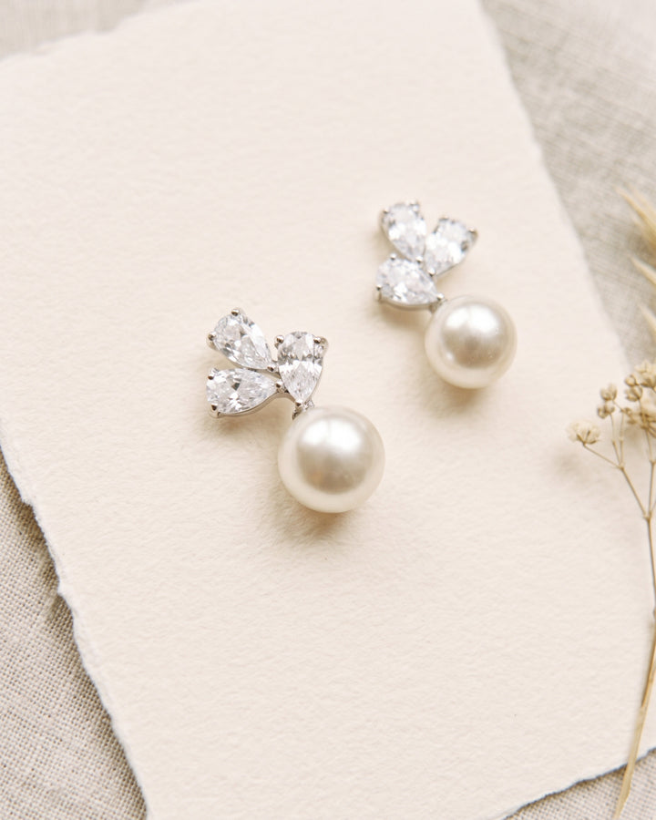 Close-up of Meadow pearl studs on deckle-edge paper showing the CZ petals and pearl