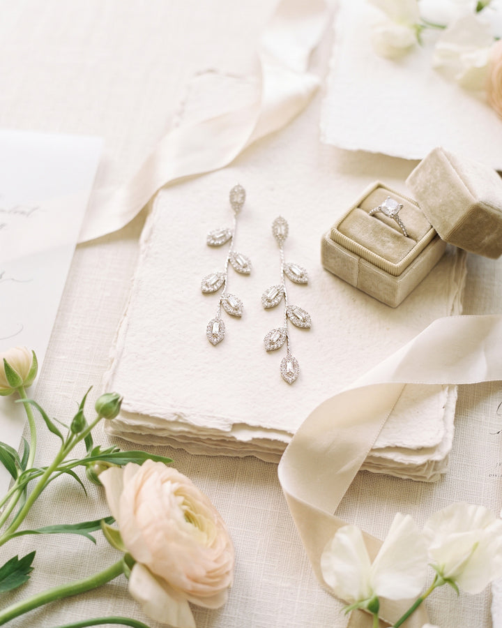 Fleur leaf earrings on stacked ivory paper with silk ribbon and pale ranunculus