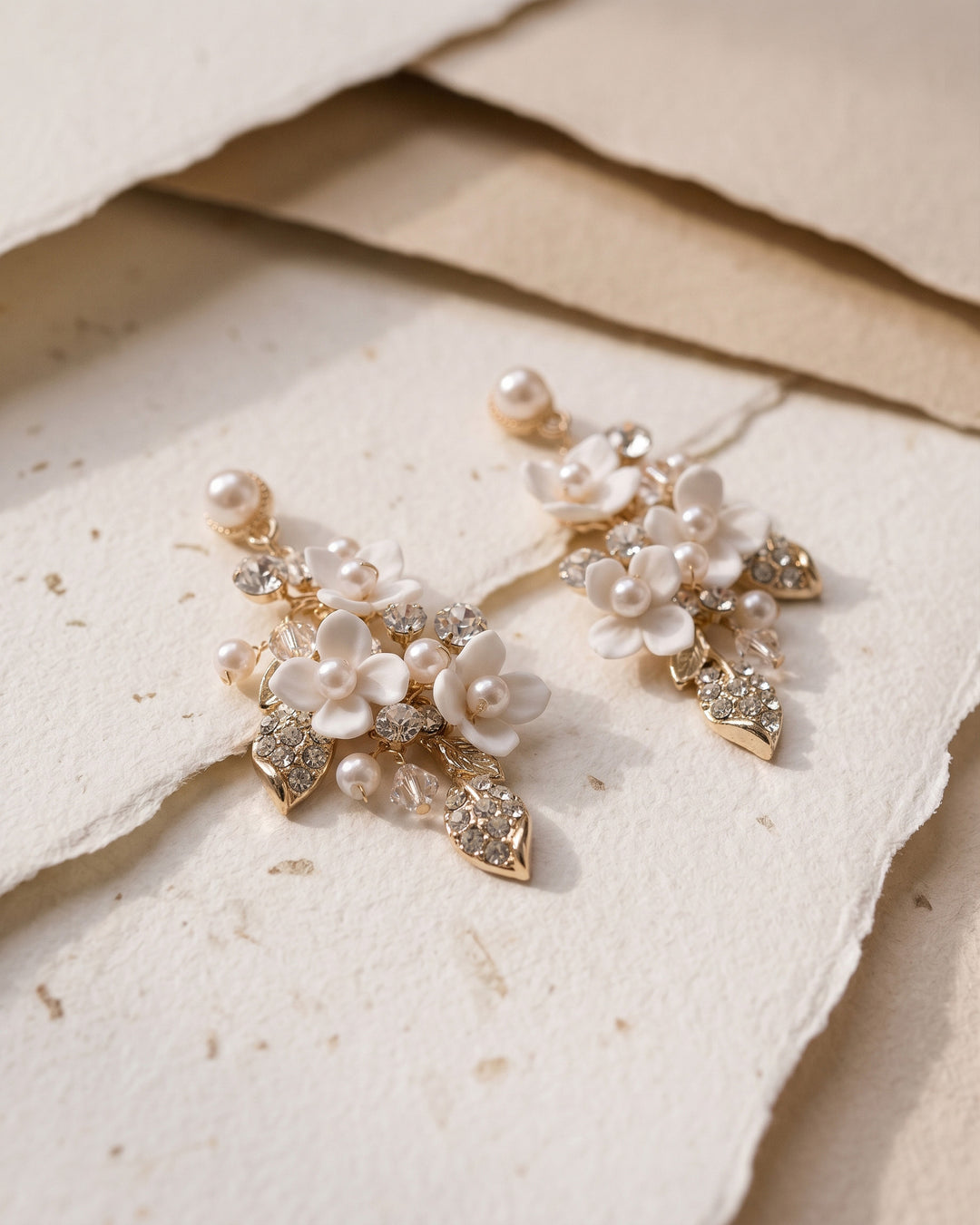 Gold Lani earrings on handmade paper, showing pearl-centered blossoms and crystal leaves