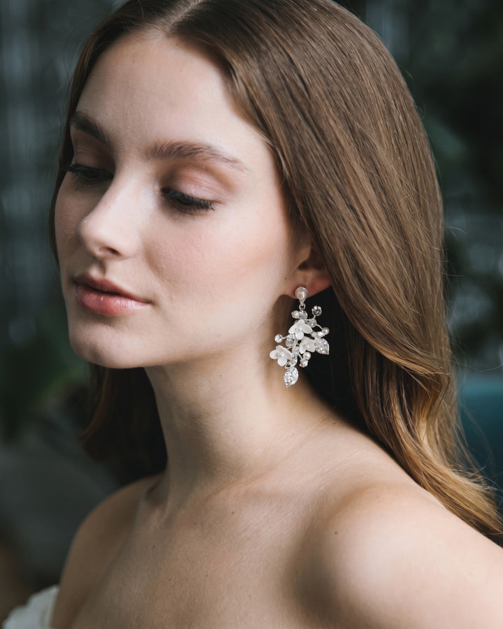 Bride with long brown hair wearing silver Lani floral earrings, shown in soft profile