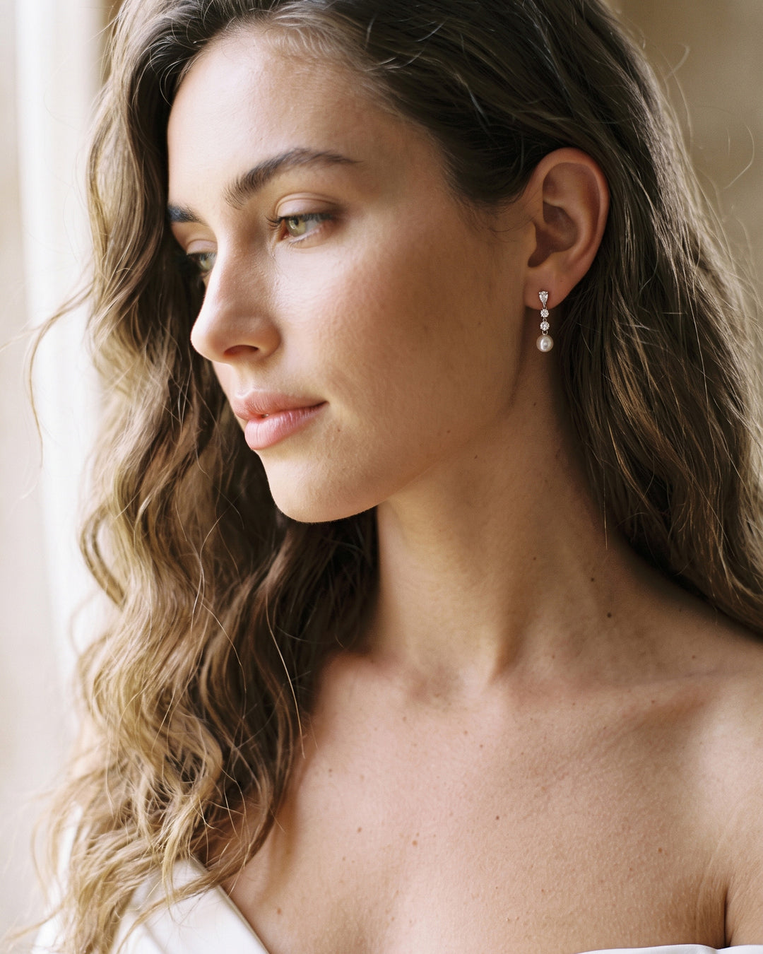 Close-up of a bride with long waves wearing the Bailey pearl and cubic zirconia earrings