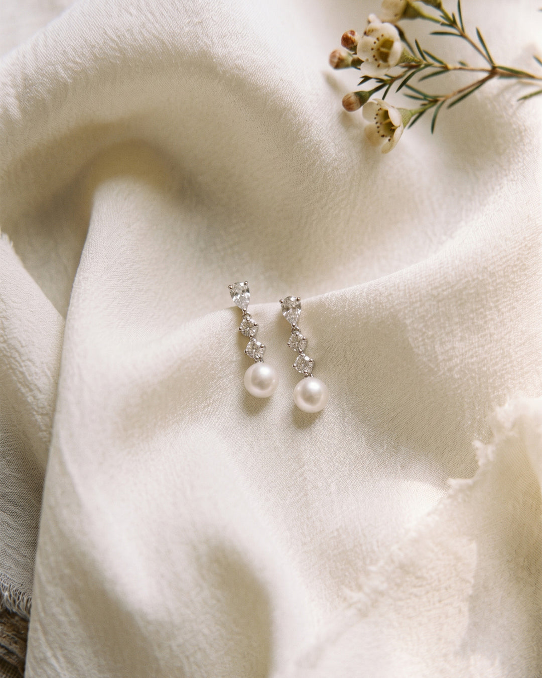 Bailey pearl drop earrings resting on ivory fabric with small white flowers