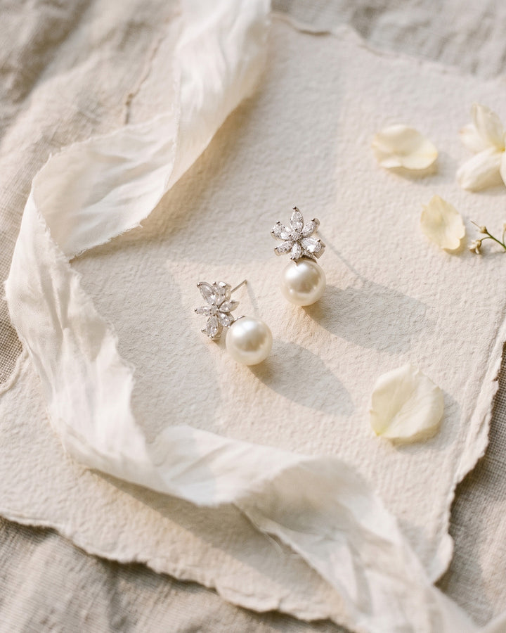 Carmen pearl studs laid on soft paper with ivory silk and scattered petals