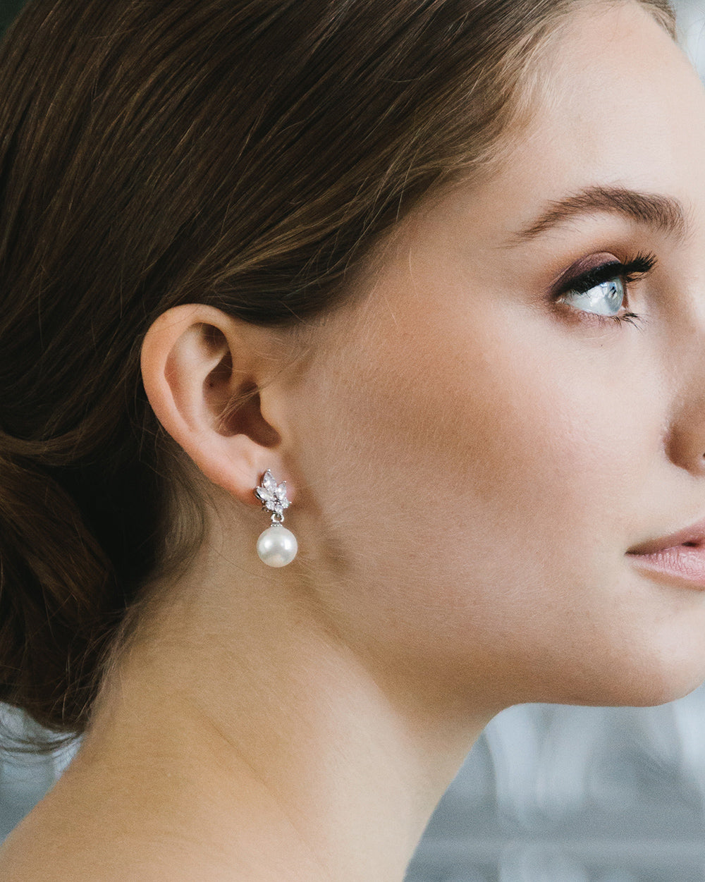 Close-up profile of the dainty Peyton earring, a light ivory pearl hanging below a sparkling floral cluster
