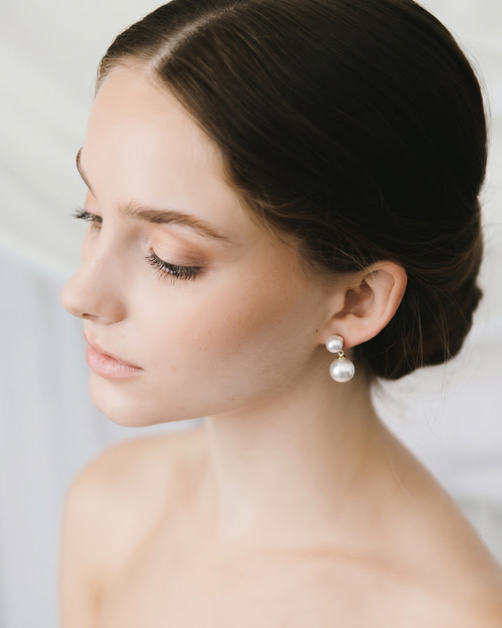 Profile of a bride with a low bun wearing the minimalist Nadine pearl drop earrings