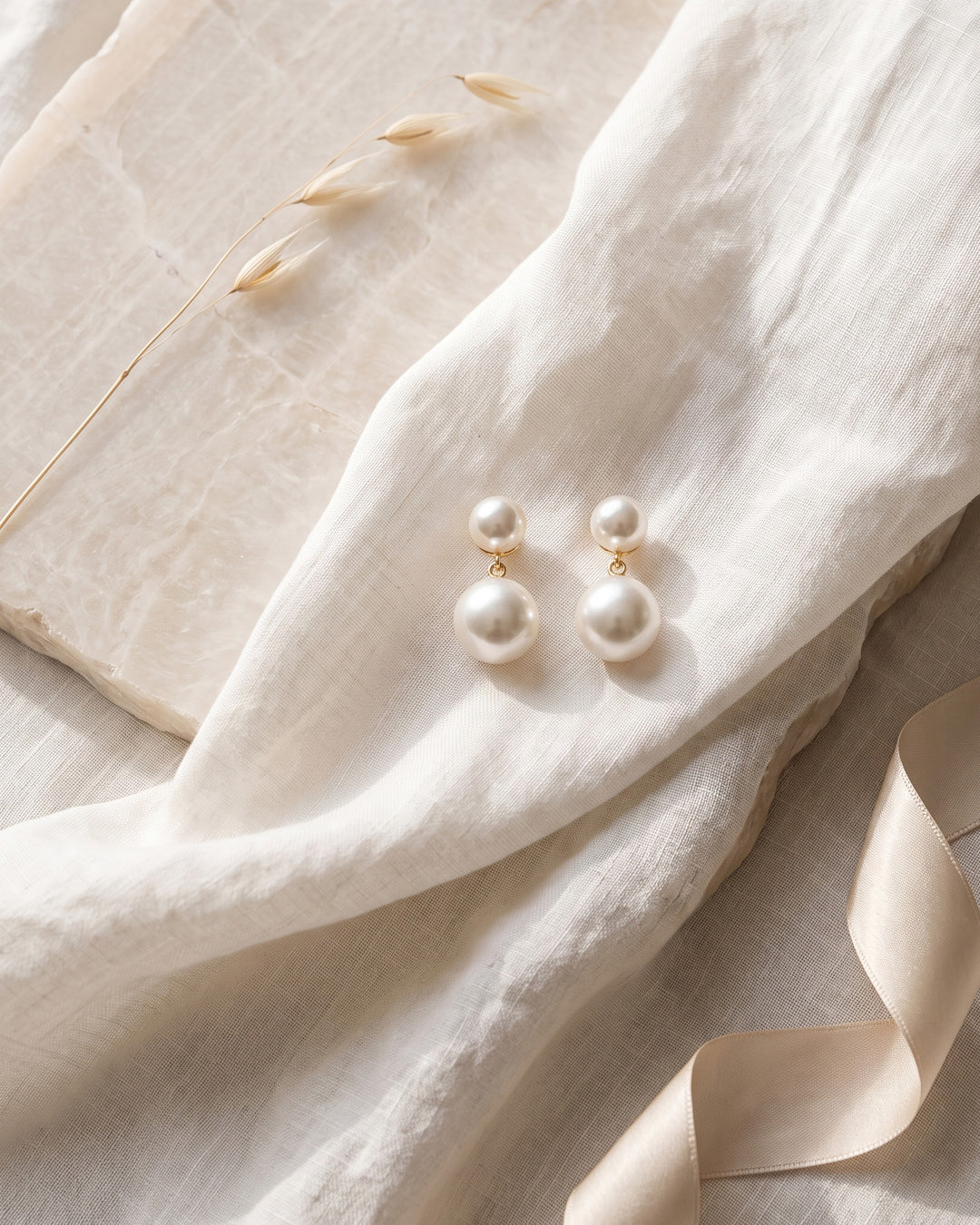Gold Nadine bridal earrings on linen and stone showing the stacked light ivory pearls