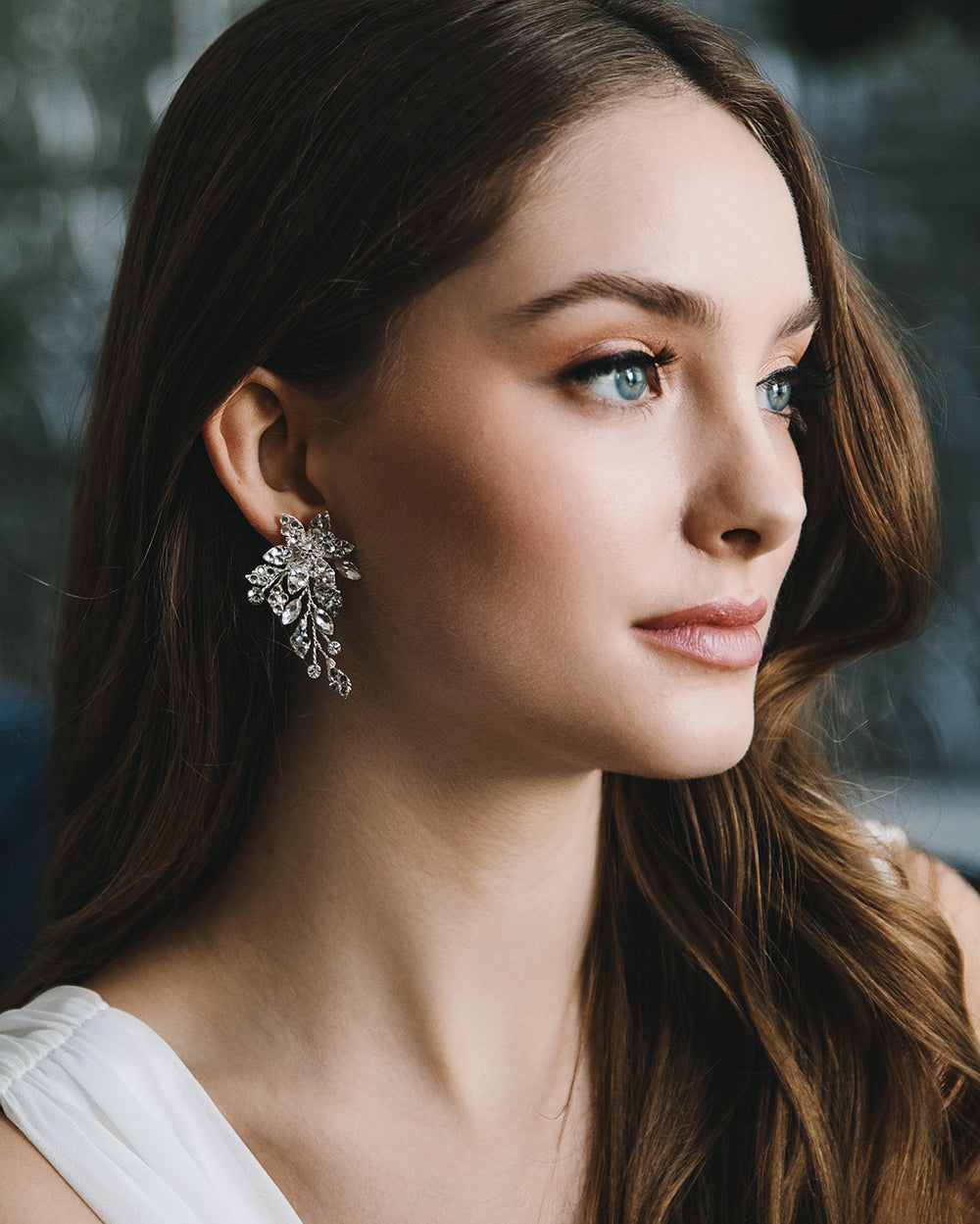 Model with long dark hair wearing the Marlena floral rhinestone wedding earrings