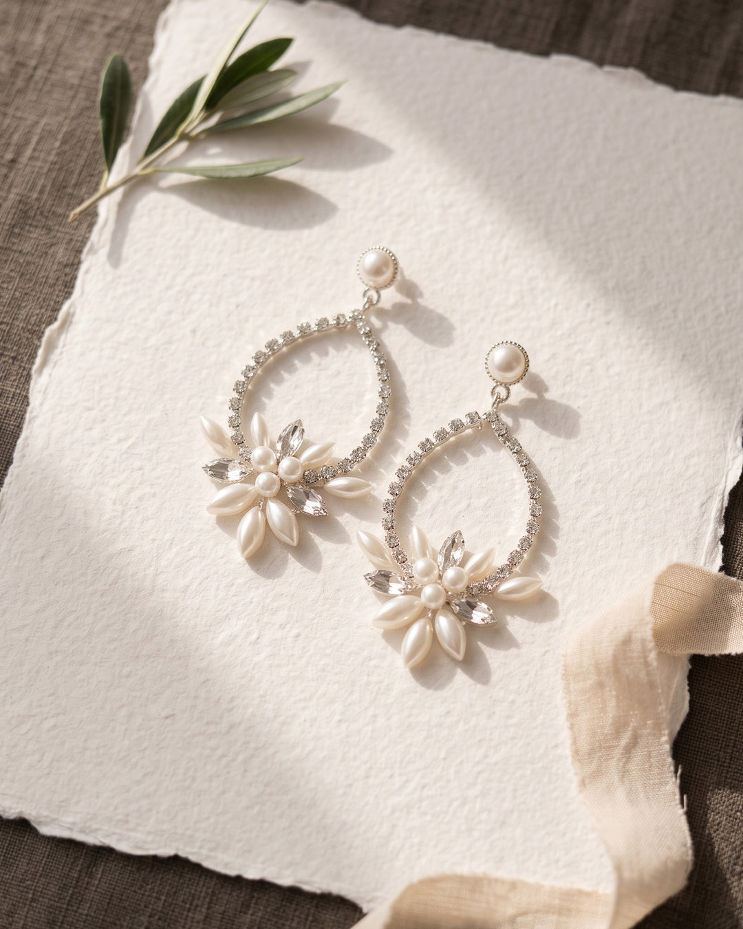 Silver Marnie earrings on handmade paper with an olive sprig and silk ribbon