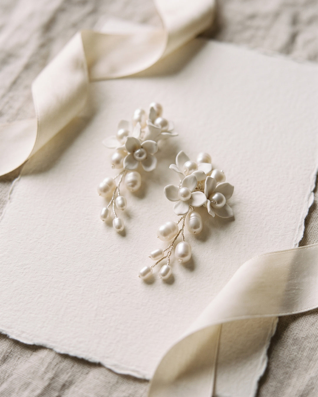 Taylor bridal earrings with asymmetrical ivory flowers and freshwater pearls on cream paper with ribbon