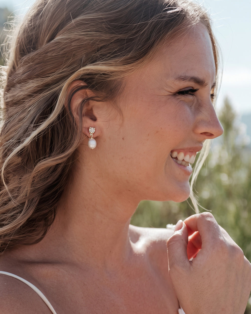 Smiling bride with soft waves wearing the Isabella gold pearl drop earrings, close-up