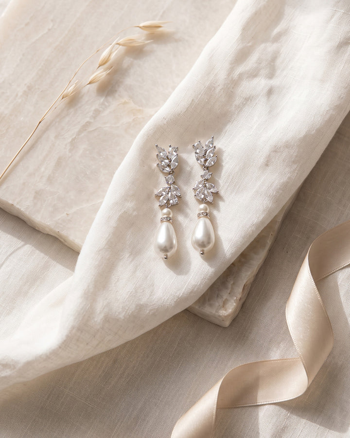 Jolene bridal earrings on linen and stone showing the teardrop pearls and CZ clusters up close