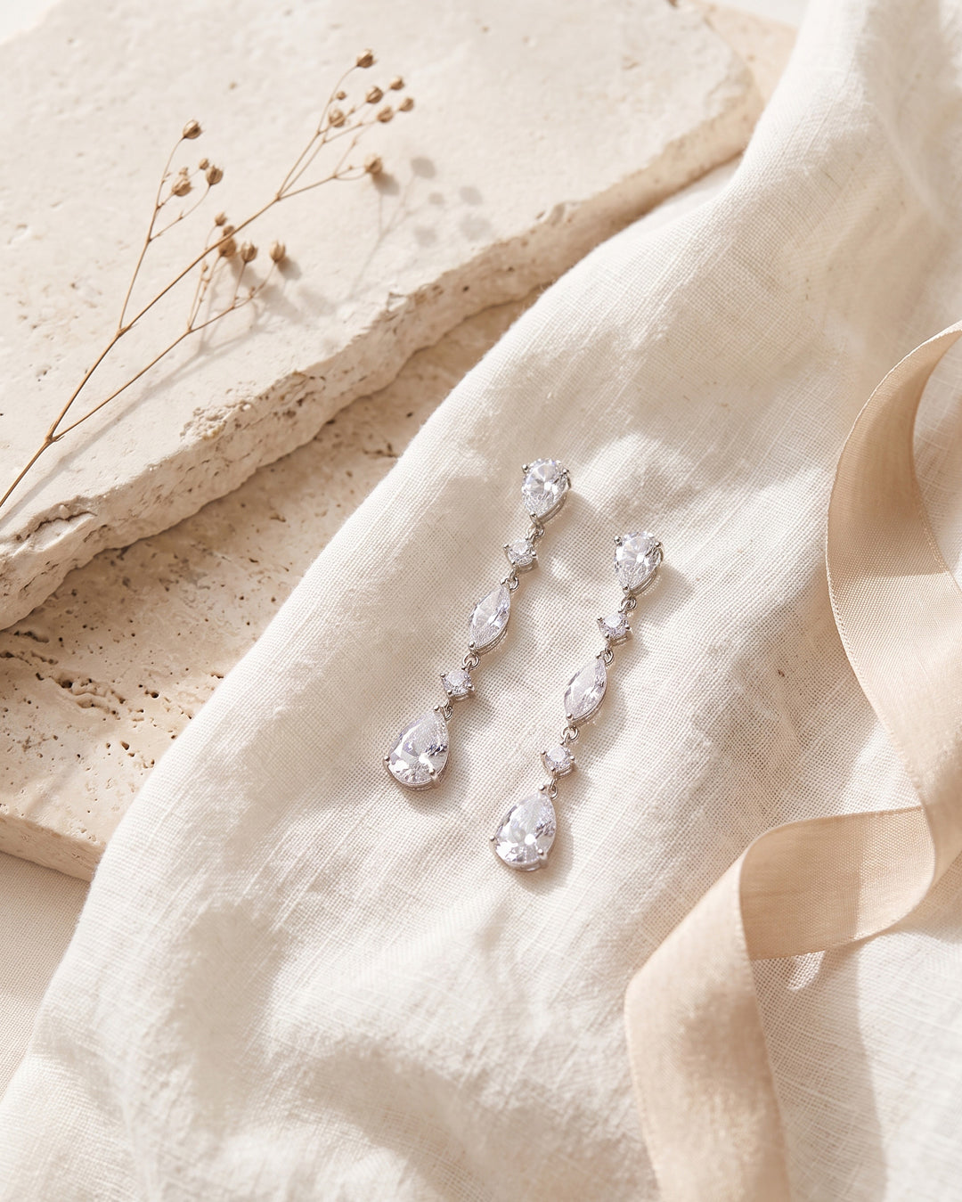 Gracie bridal earrings on linen and stone showing each pear and marquise cubic zirconia up close