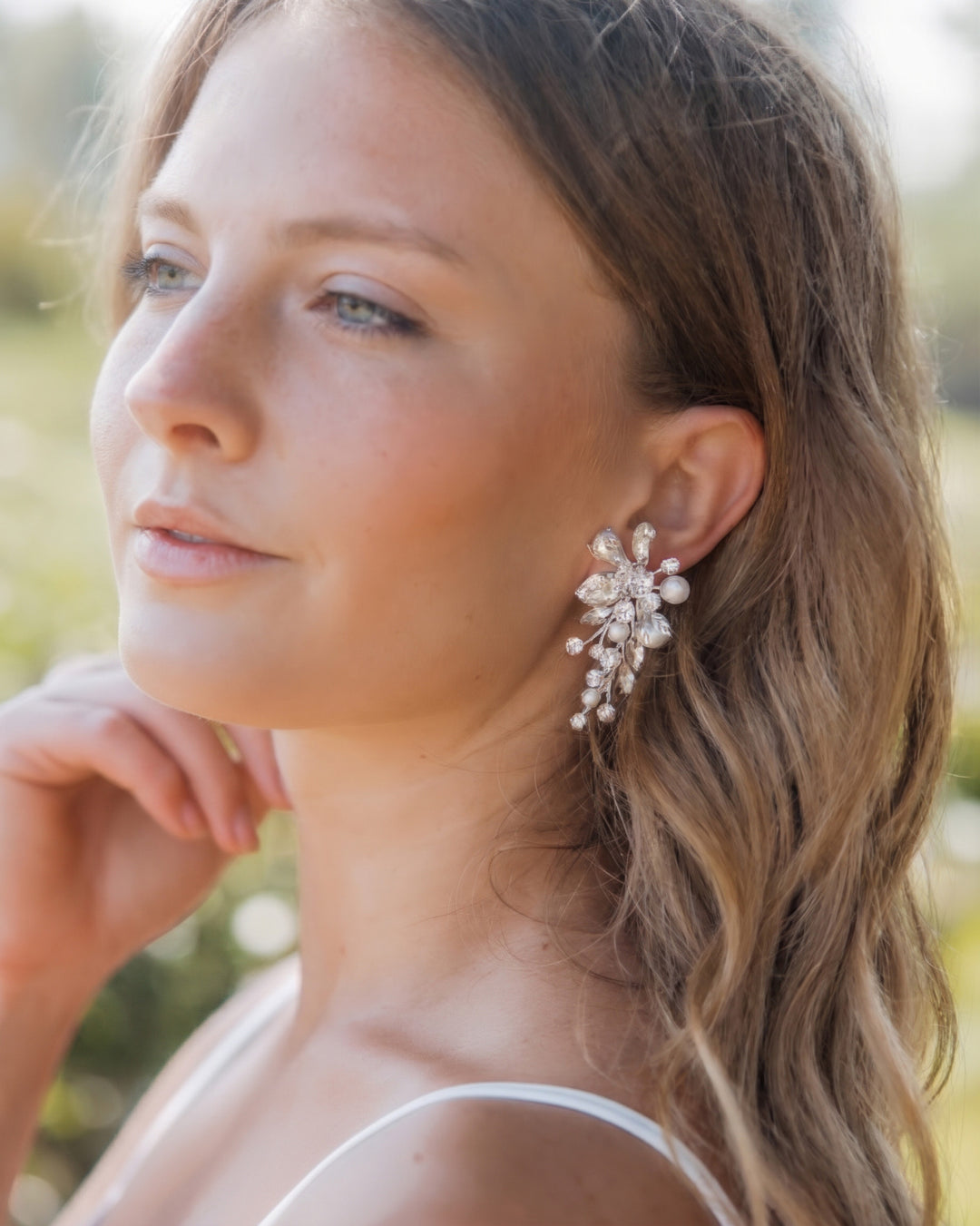 Bride with soft waves wearing the Alessia statement earrings, pearls and crystals cascading below the ear