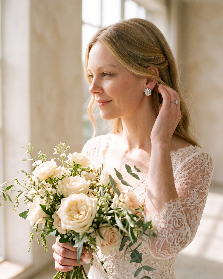 Bride by a sunlit window with a rose bouquet, wearing Sienna CZ studs