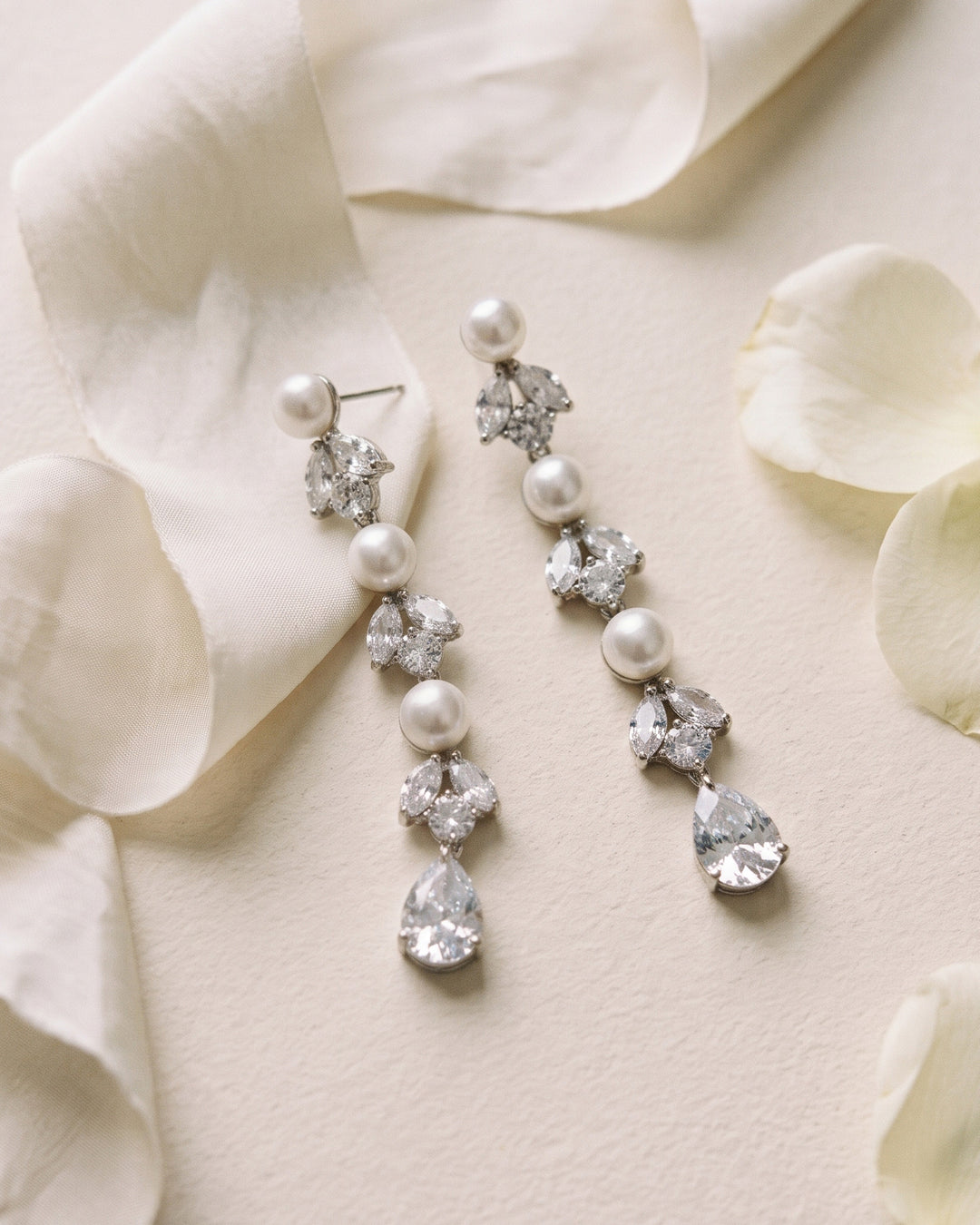 Maxine pearl statement earrings on ivory silk with scattered petals