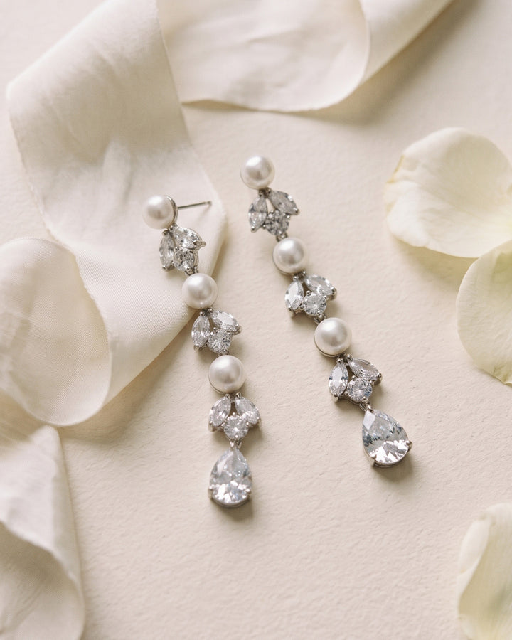 Maxine pearl statement earrings on ivory silk with scattered petals