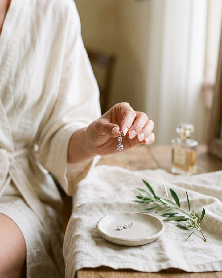 Bride holding a Nadia cubic zirconia earring at a table with olive sprigs
