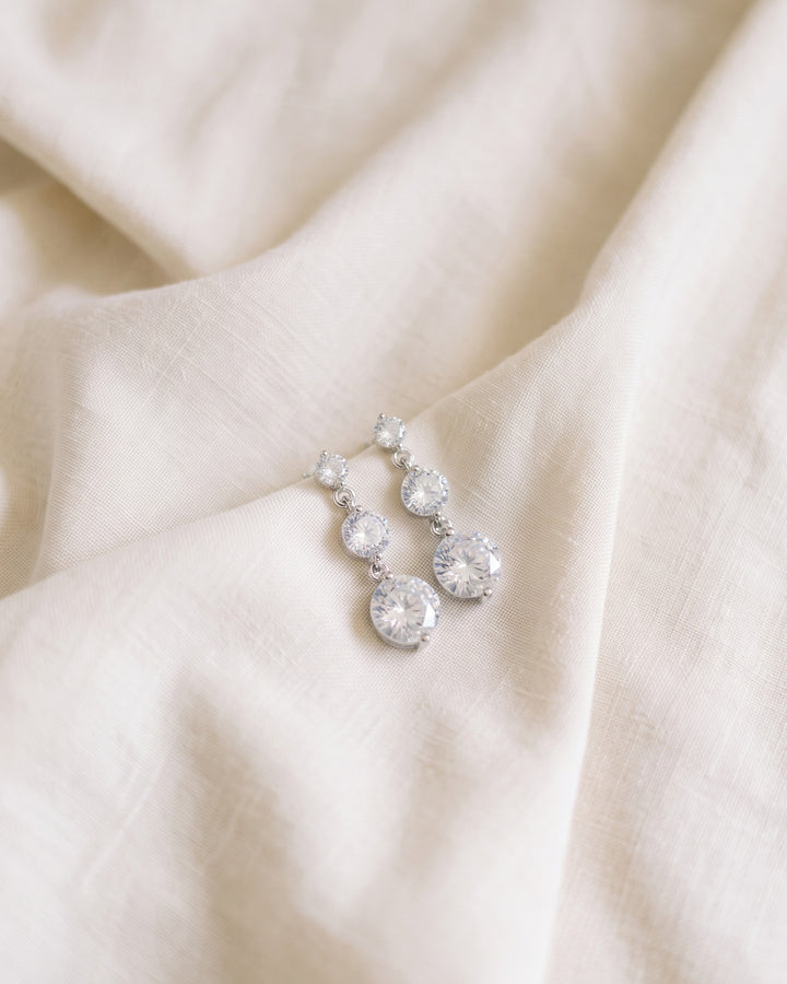 Nadia cubic zirconia bridal earrings resting on ivory linen