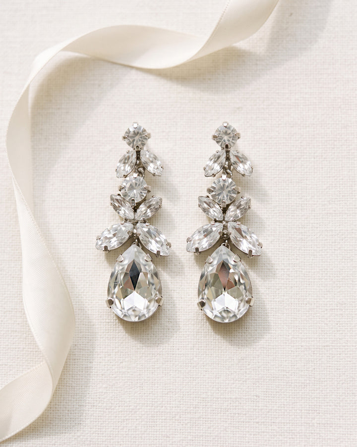 Pair of Tiana bridal earrings laid flat, marquise crystal clusters graduating down to a large teardrop crystal