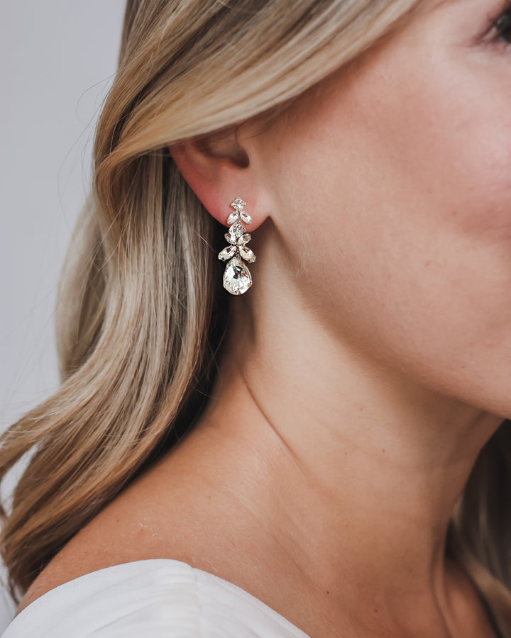 Bride wearing Tiana crystal drop earrings with long, side-swept waves, showing the teardrop at the jaw