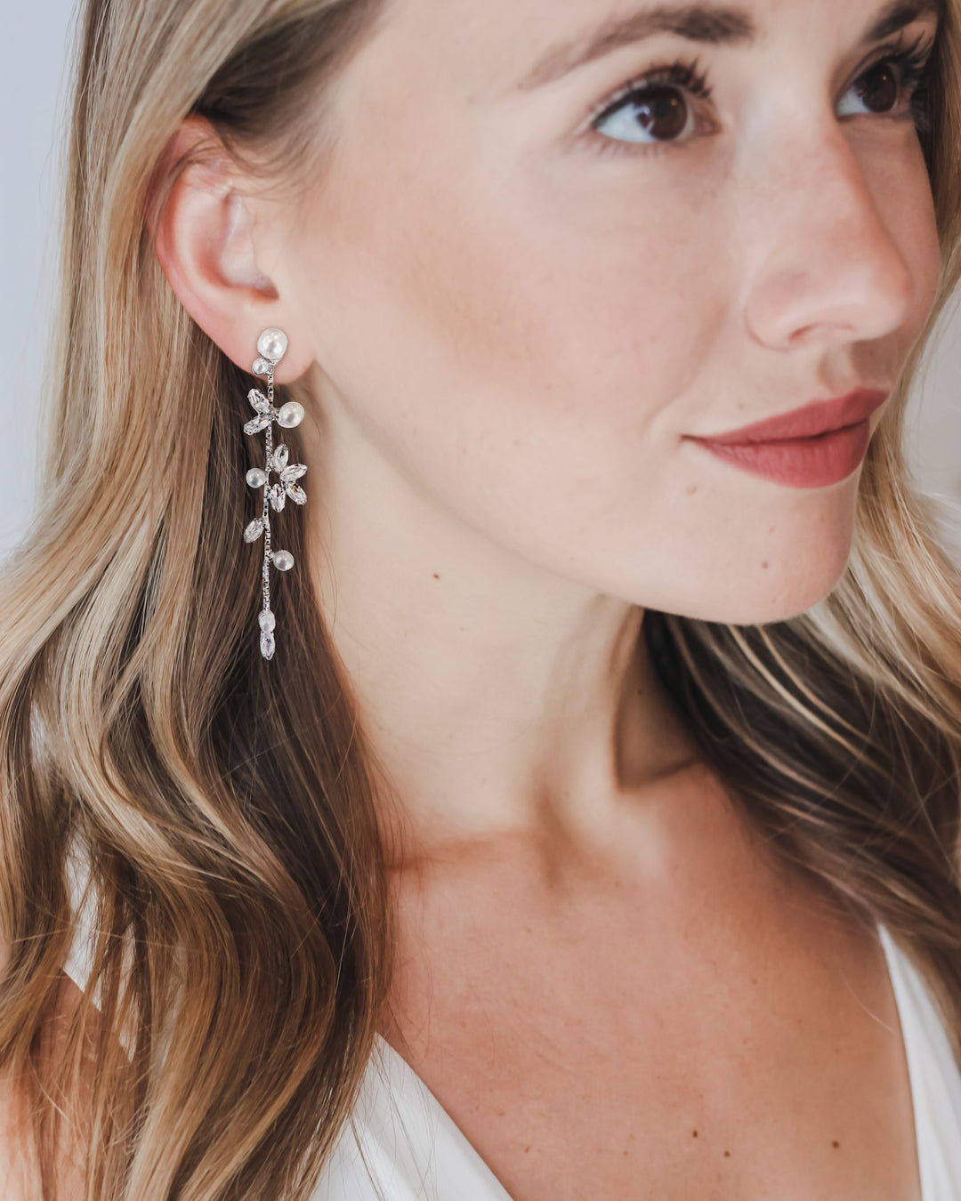 Bride wearing Katrina pearl and cubic zirconia drop earrings with long, loose waves and a V-neck